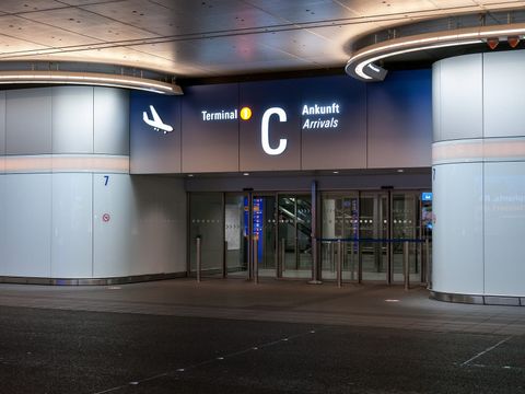 Beleuchteter Eingang zur Ankunftshalle Terminal 1 C am Flughafen Frankfurt bei Nacht
