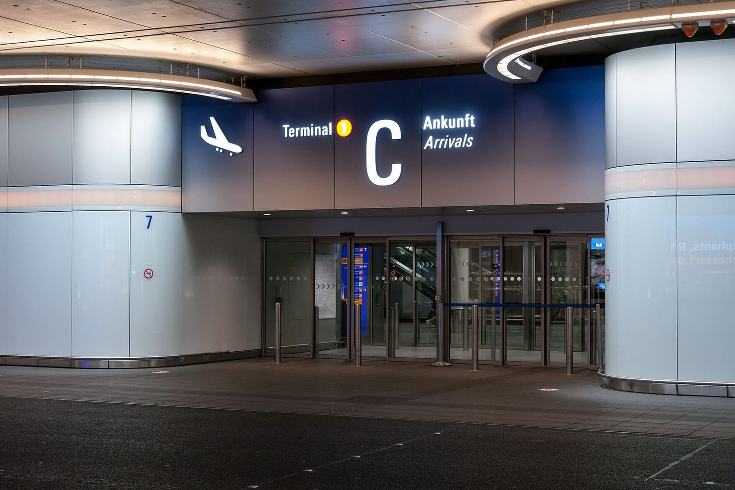 Beleuchteter Eingang zur Ankunftshalle Terminal 1 C am Flughafen Frankfurt bei Nacht