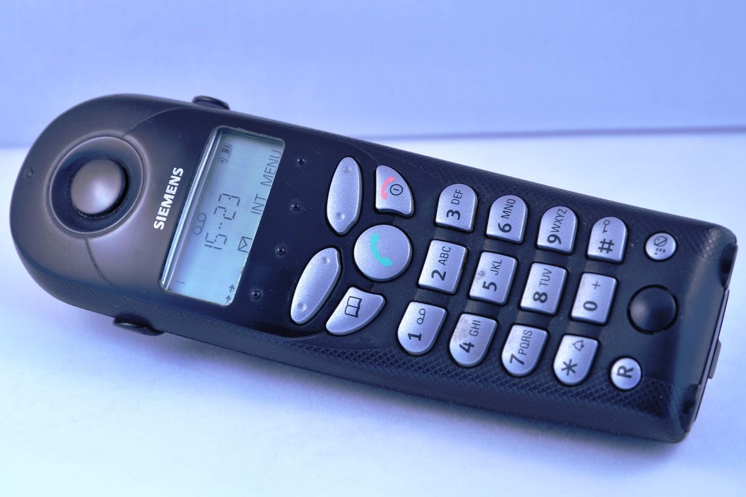 Black cordless landline handset with display and silver keypad on a light background