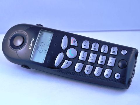 Schwarzes schnurloses Festnetztelefon mit Display und silbernen Tasten auf hellem Grund