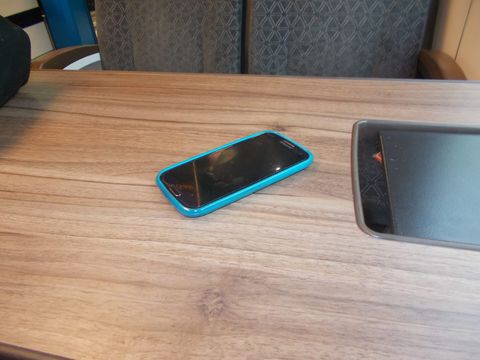 Smartphone with a dark screen in a turquoise case lying on a train table