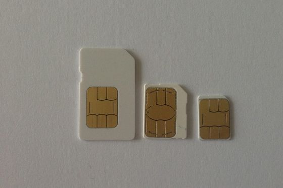 Three SIM cards in standard, micro and nano sizes side by side on a light surface